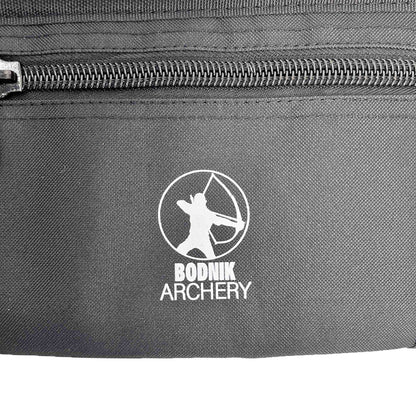 Schwarzer Stoff mit sichtbaren Nähten sowie ein Reißverschluss. Mittig ein weißes Logo, das eine stilisierte Figur mit gespanntem Bogen im Kreis darstellt. Darunter der Schriftzug "BODNIK ARCHERY".