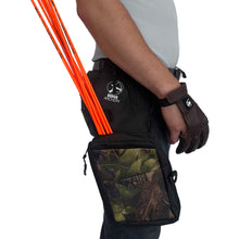 Person trägt grau meliertes Shirt, dunkle Hose, schwarzen Camouflage-Holsterköcher mit Bodnik Archery-Logo, mehrere orange Pfeile, brauner Schießhandschuh