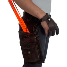 Person trägt braunen Holsterköcher aus Leder mit orangefarbenen Pfeilen an der Hüfte, brauner Schießhandschuh an der Hand