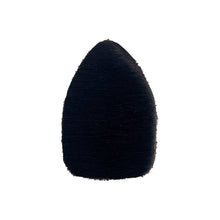 Ein schwarzes Objekt in Tropfenform mit einer strukturieren, leicht fransigen Oberfläche. Die Spitze zeigt nach oben.