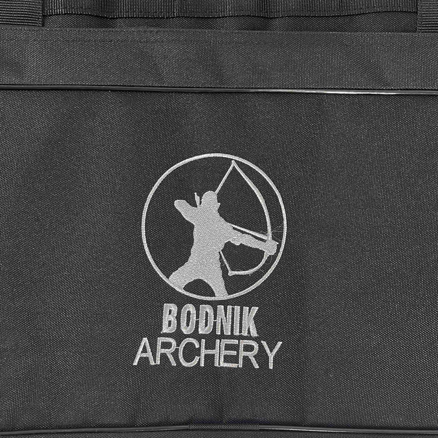 Schwarzes Gewebe mit aufgesticktem Bodnik Archery Logo, darüber eine Bogenschützensilhouette im Kreis sowie Teil eines Reisverschlusses oben.
