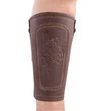 Brauner Armschutz aus Leder mit hellbraunen Nähten auf Unterarm getragen, Prägung mit Motiv eines bewaffneten Tieres.