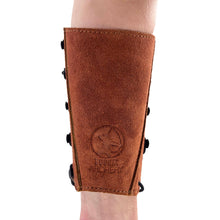 Ein brauner Armschutz aus Wildleder, mit schwarzem Knopfverschluss an der Seite und Bodnik Archery Logo auf der Vorderseite.