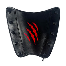 Schwarz glänzender Armschutz aus Leder mit neun schwarzen Nieten, rotem Krallenmuster in der Mitte, leicht gewölbte Form.